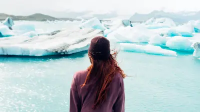 Uma mulher em frente a um lago glacial. 
