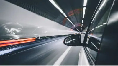 Um carro dirigindo através de um túnel; os outros veículos só são reconhecíveis como luzes borradas. 