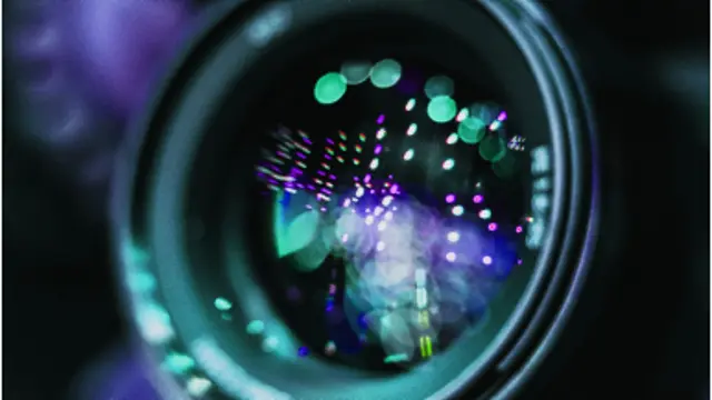 O close-up de uma lente de câmera com luzes tocando fora dela.