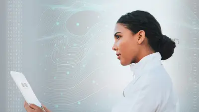 A woman stands in front of a digital wall displaying abstract data patterns. She holds a tablet in her hand and looks confident.